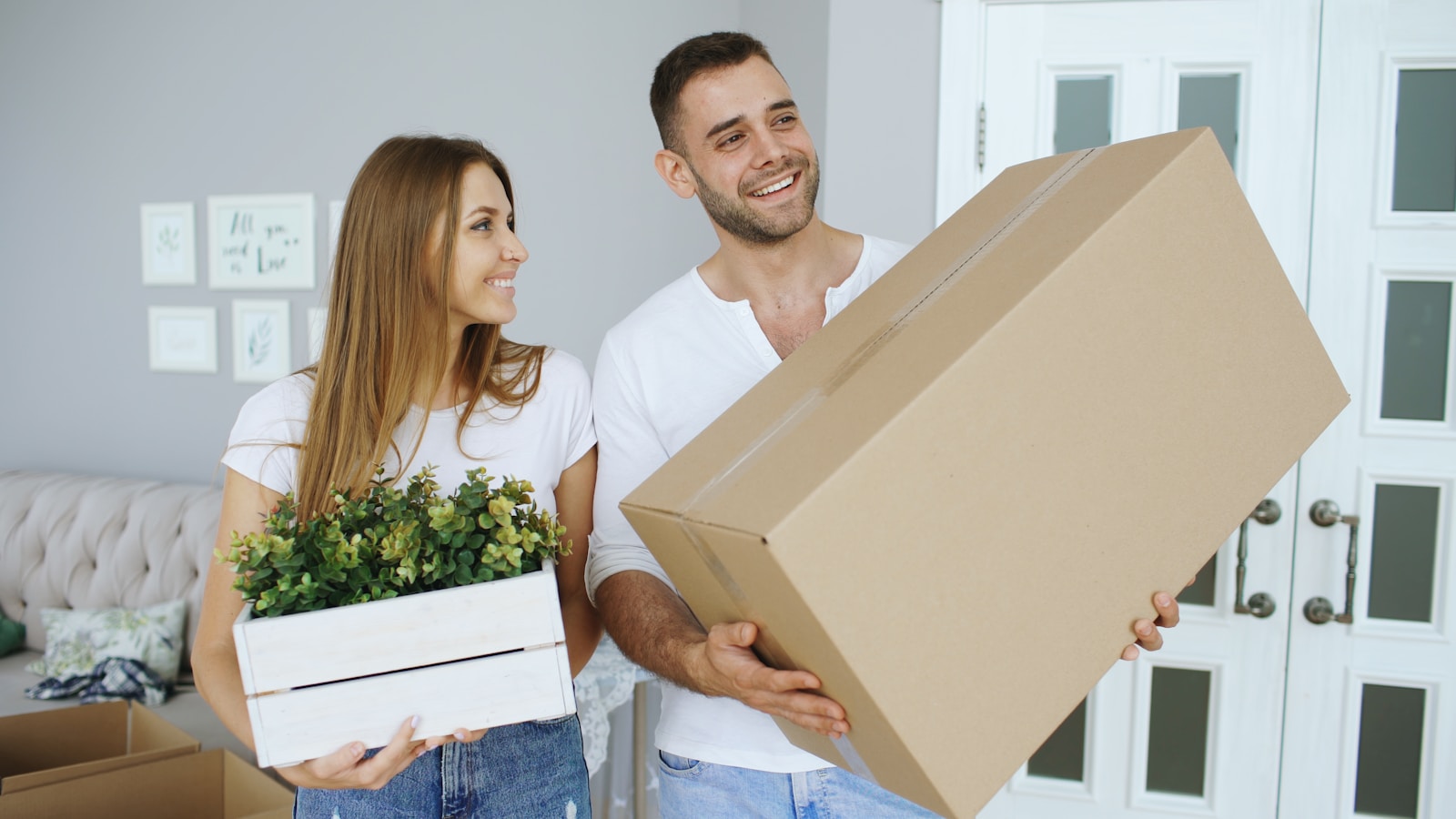 Couple carrying a large box and a plant, renters